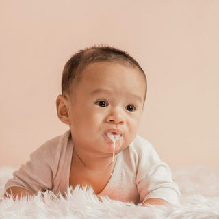 Why do newborn babies spit up or vomit milk after feeding?